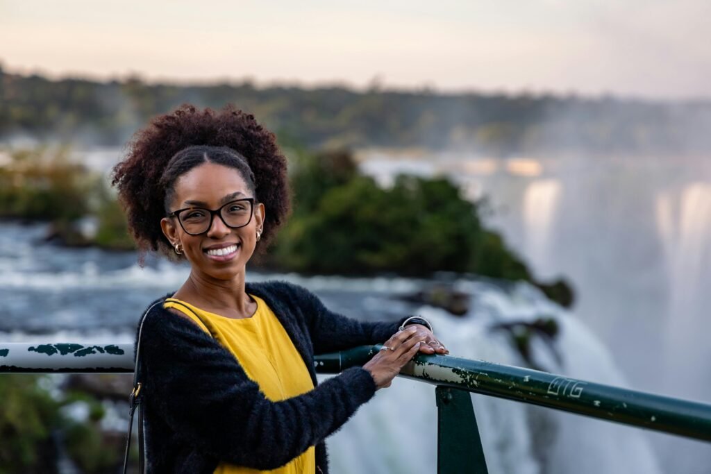 Woman smiling at Iguazu Falls railing with scenic background.